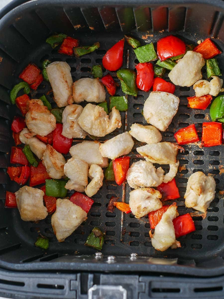 Chicken and peppers in an air fryer.