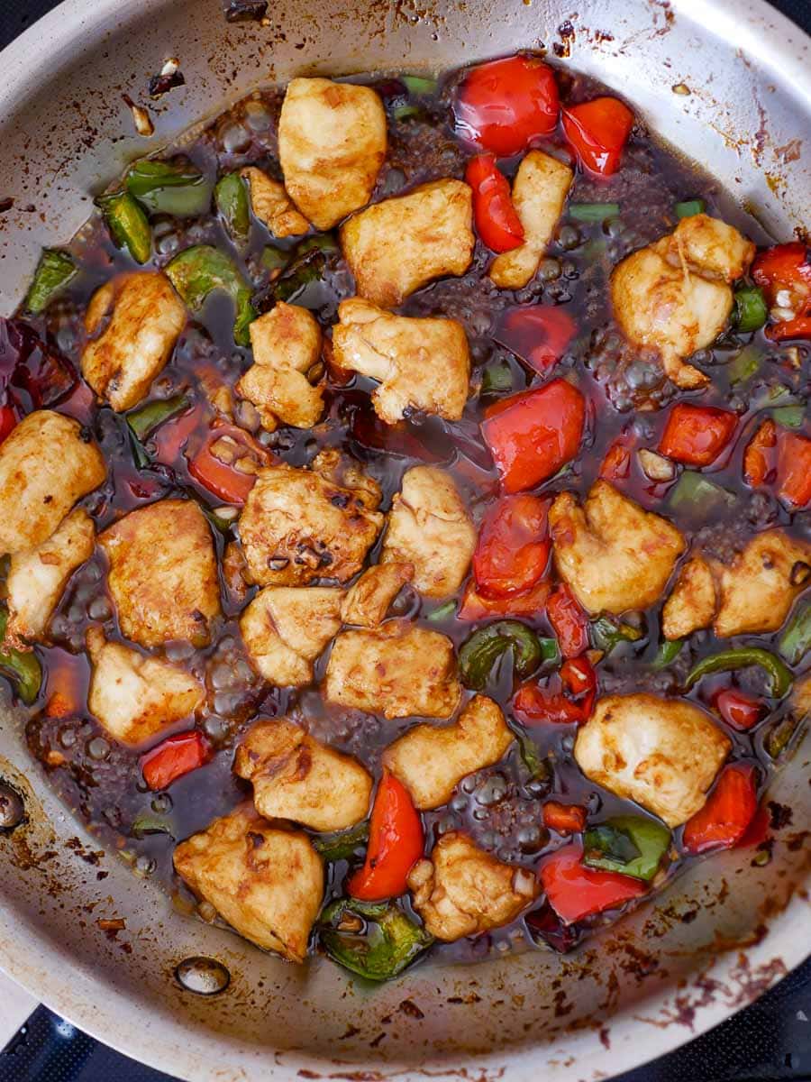 A frying pan with chicken and peppers.