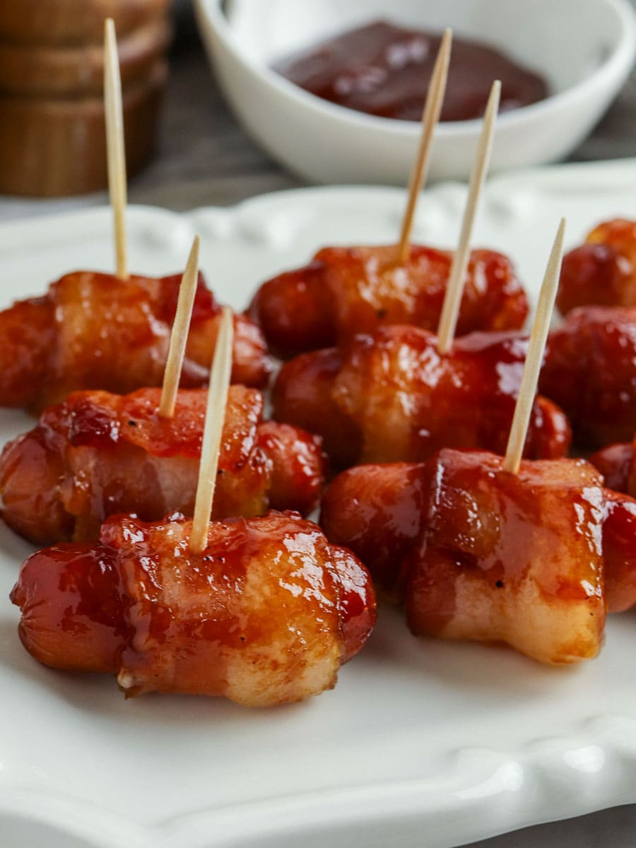 bacon wrapped little smokies on toothpicks on a plate.