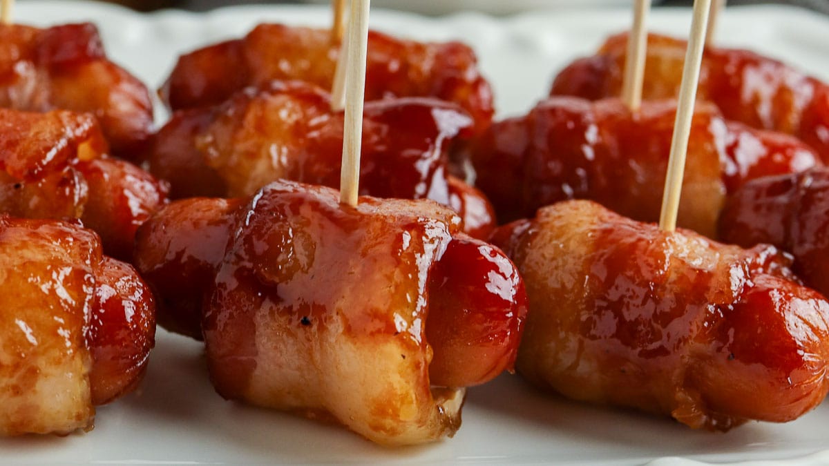 bacon wrapped little smokies with toothpicks on a plate.
