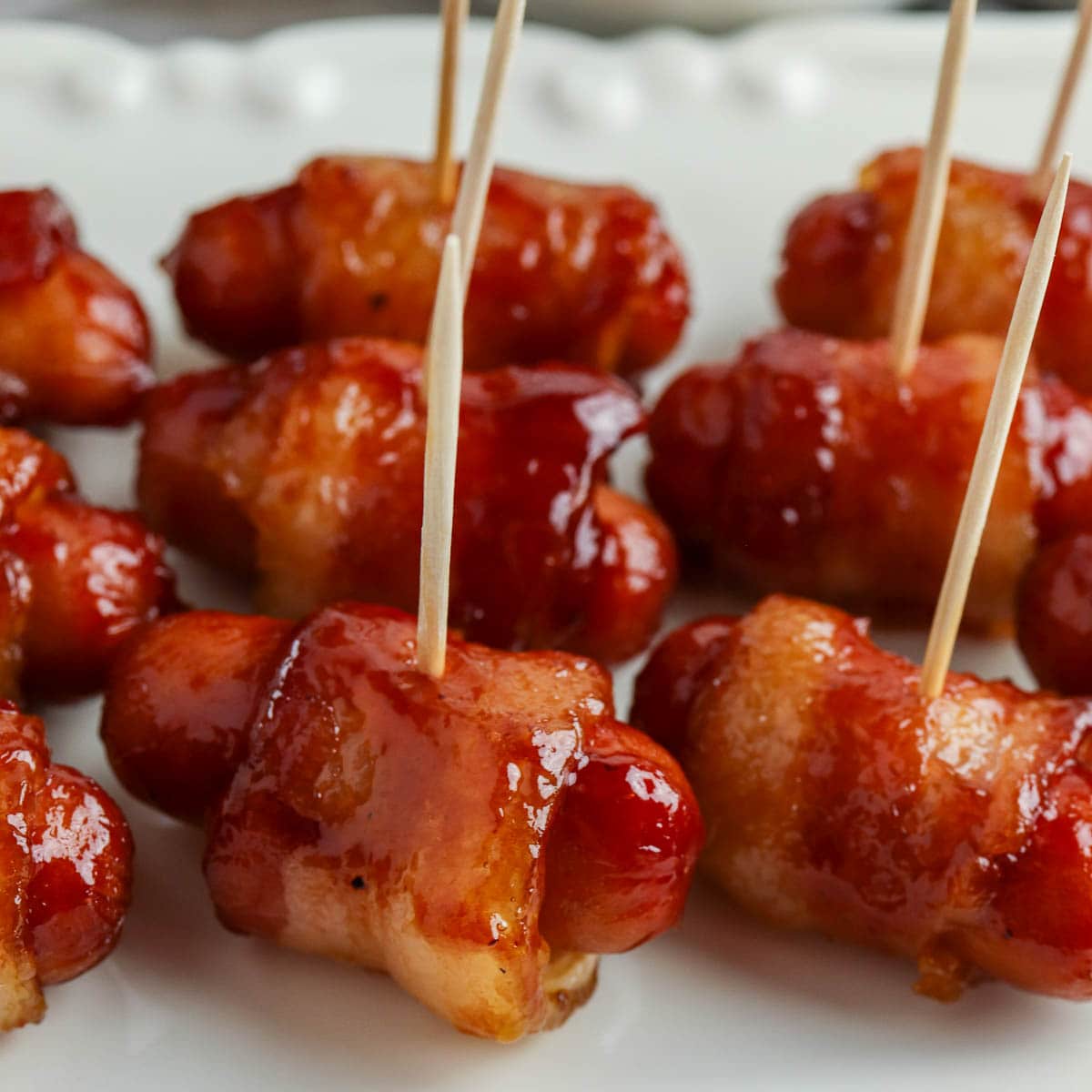 bacon wrapped little smokies with toothpicks on a plate.