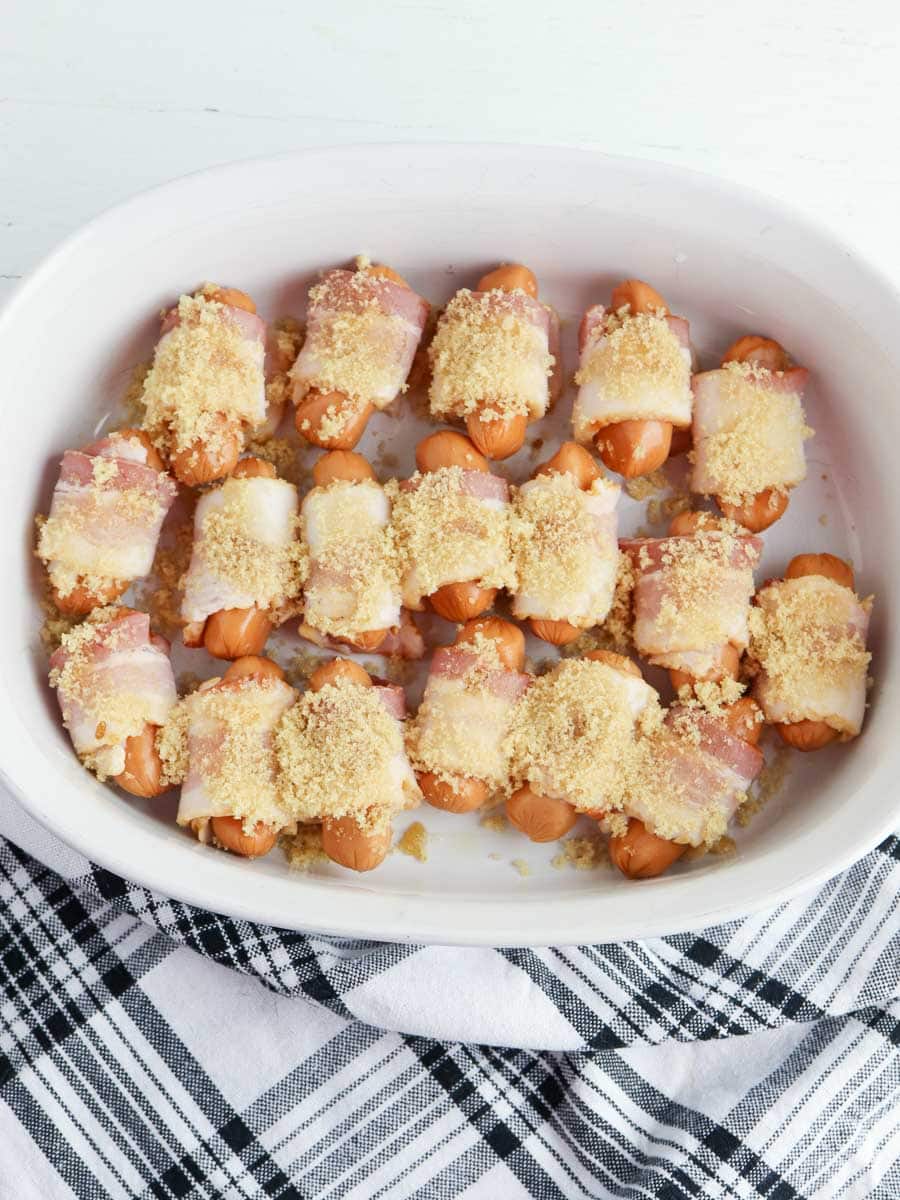 bacon wrapped little smokies in a white baking dish.