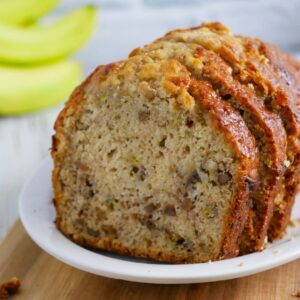 A freshly baked loaf of banana bread with a slice cut out, revealing the moist texture and chunks of banana inside.