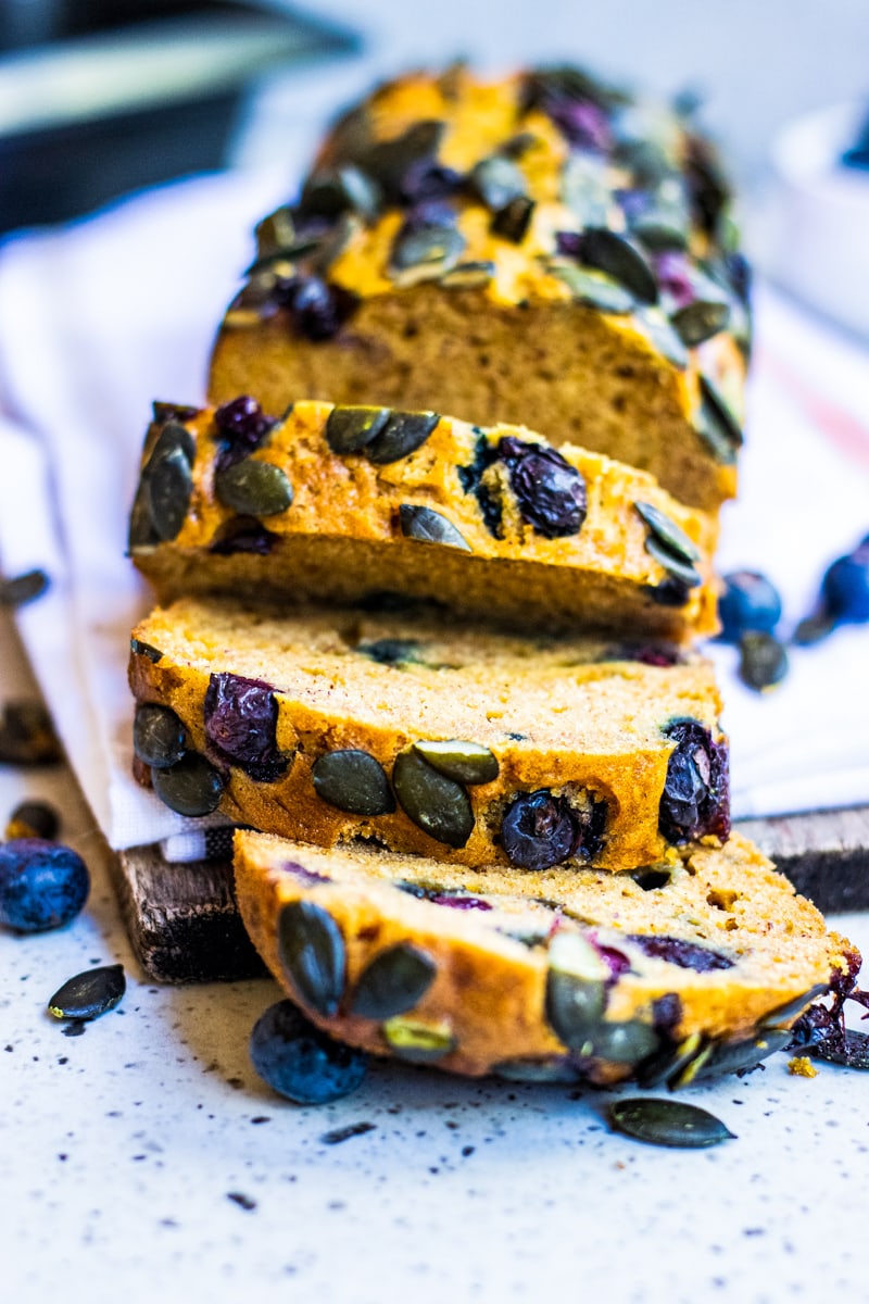 Sliced blueberry pumpkin bread on a white surface.