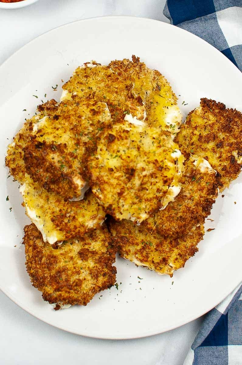A plate of fried mozzarella drizzled with a light sauce.