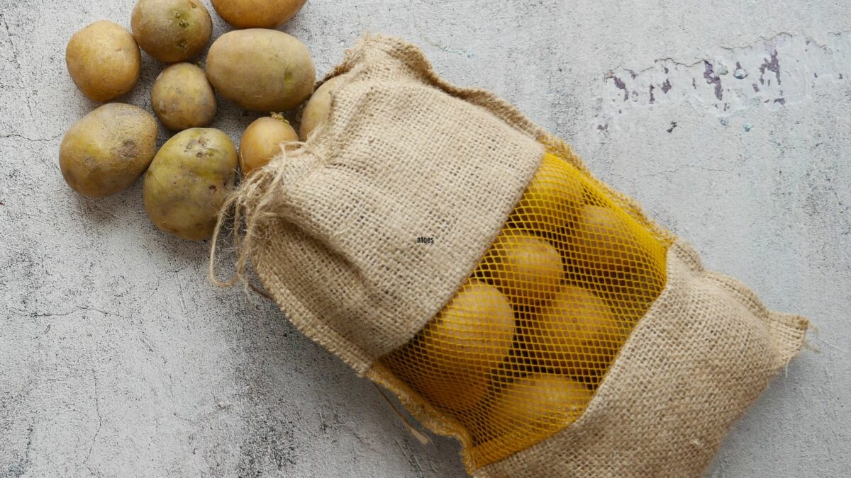 Potatoes in a sack on a white surface.