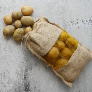 Potatoes in a sack on a concrete surface.
