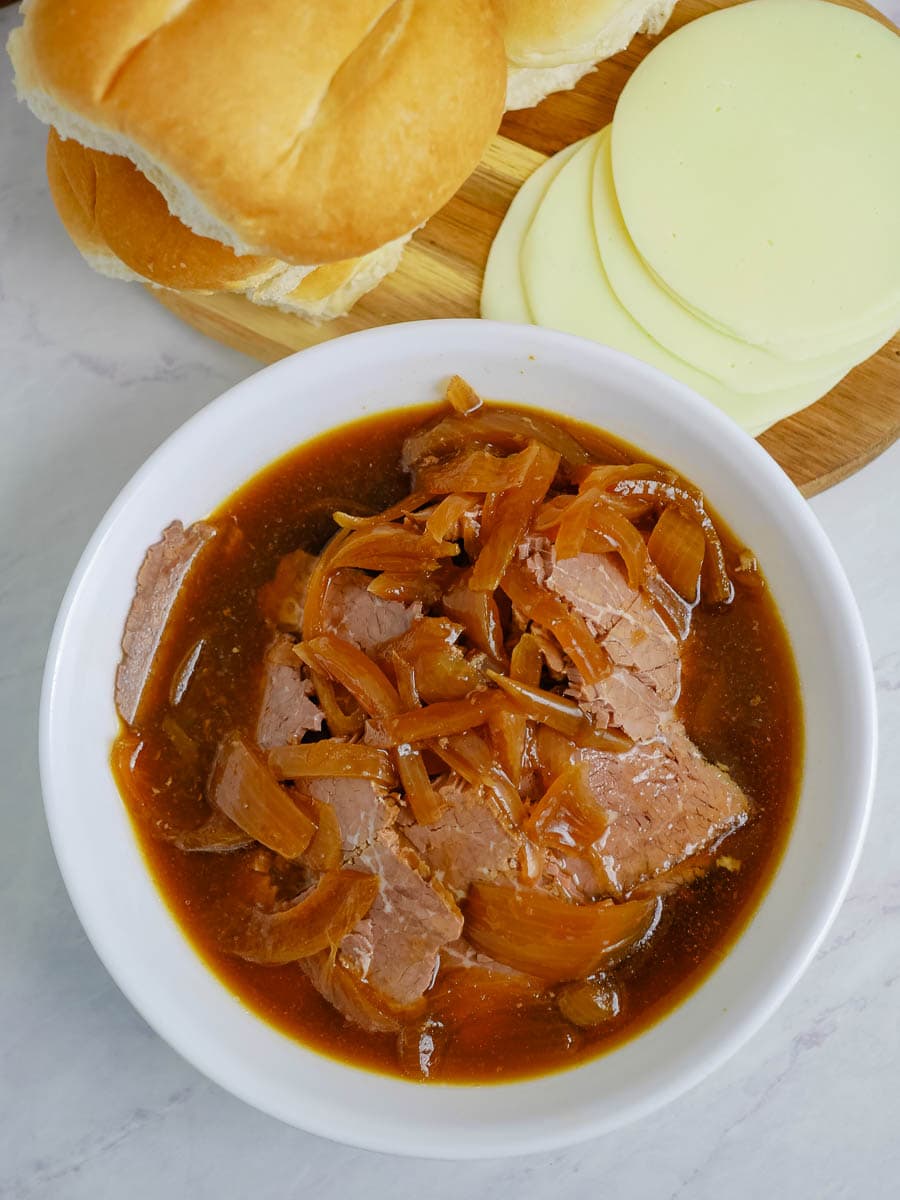 A bowl of stew with meat, onions and bread.