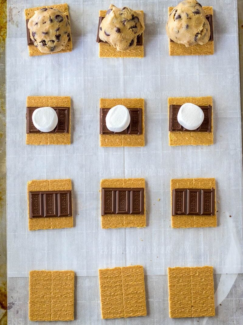 Ingredients for s'mores and cookie s'mores laid out on a baking sheet in preparation for assembly.
