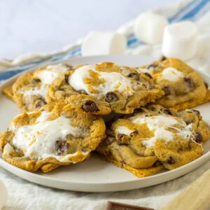 A plate of freshly baked chocolate chip cookies with melted marshmallows on top.
