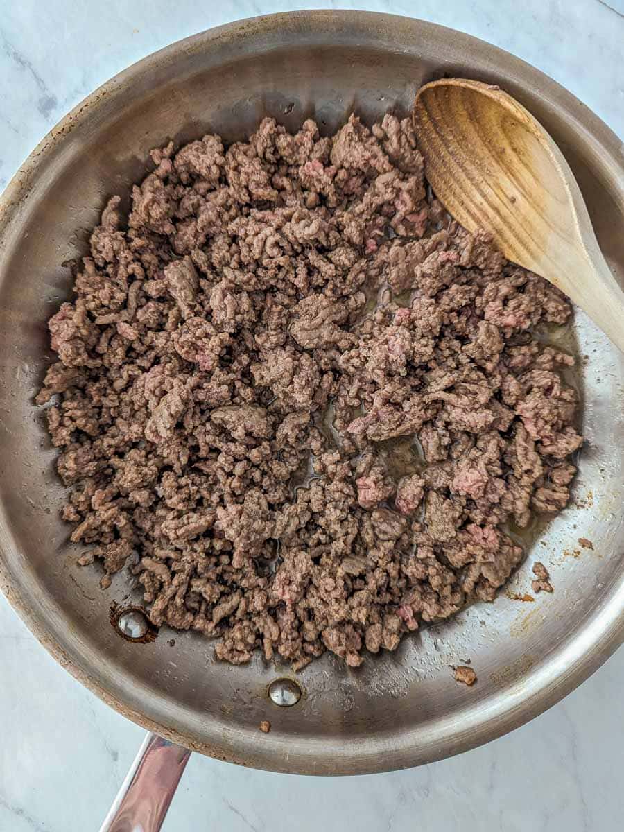 Ground beef in a pan with a wooden spoon.