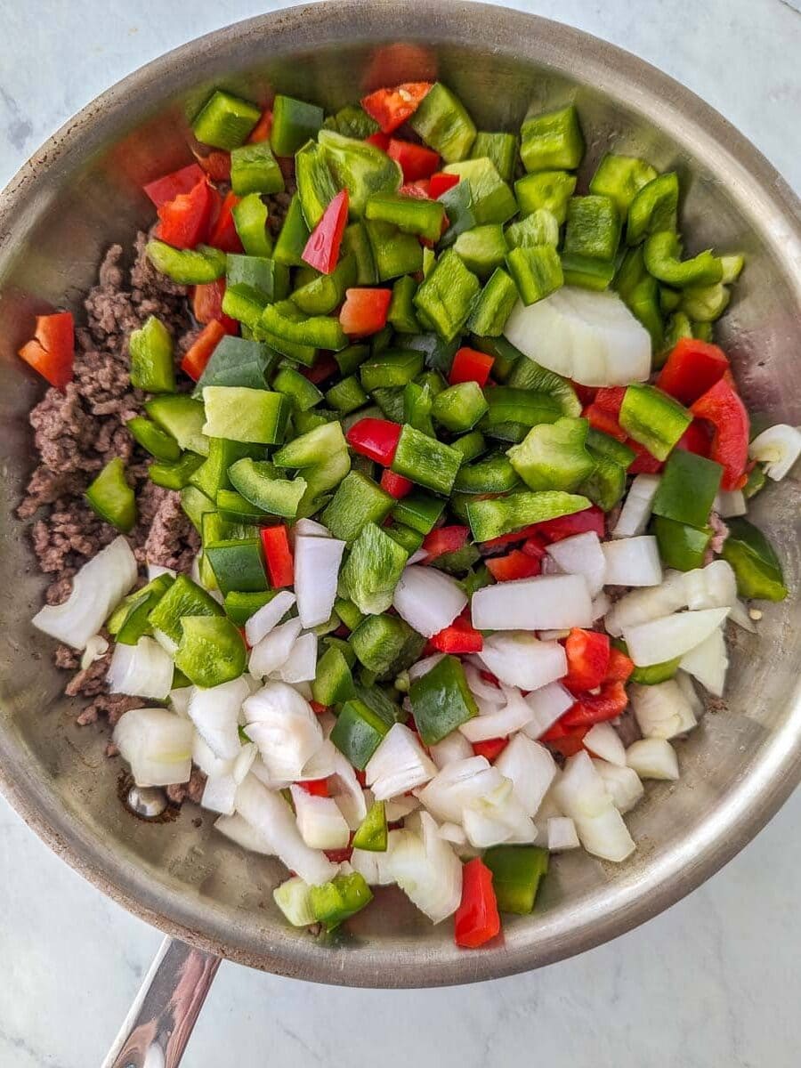 A pan with onions, peppers, and beef in it.