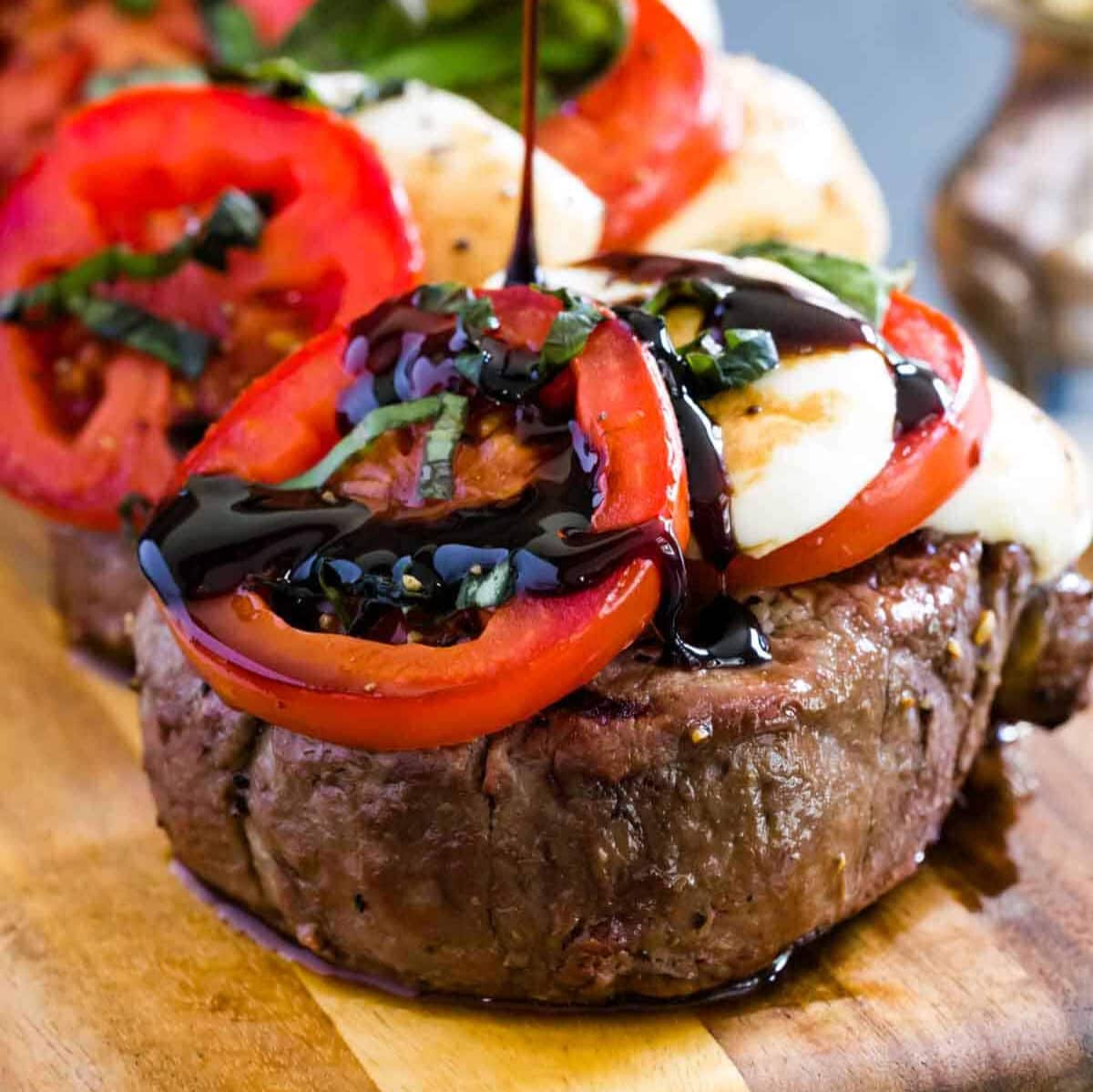 Grilled steak topped with sliced tomatoes, mozzarella, and drizzled with balsamic reduction.