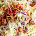 A colorful broccoli slaw salad featuring shredded broccoli, carrots, purple cabbage, sunflower seeds, and bacon bits, topped with a creamy dressing. text overlay highlights the dish's features.