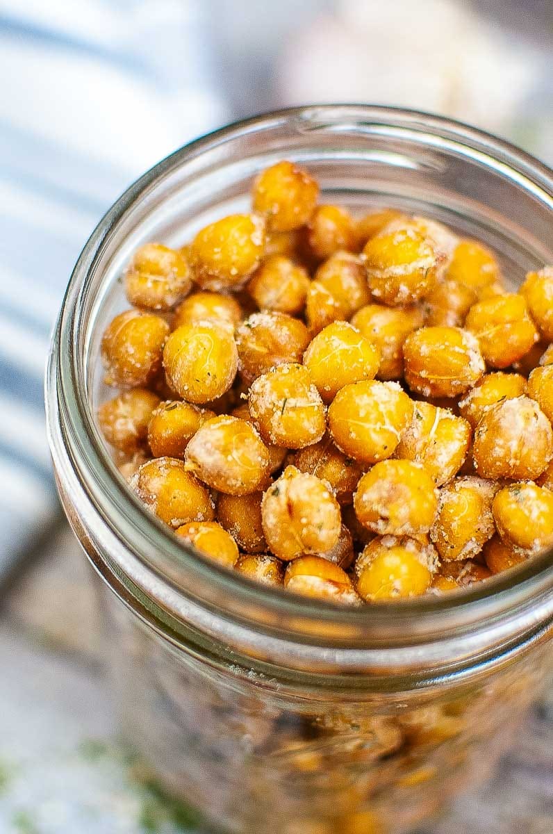 A close-up of a jar filled with crispy roasted chickpeas seasoned with spices.