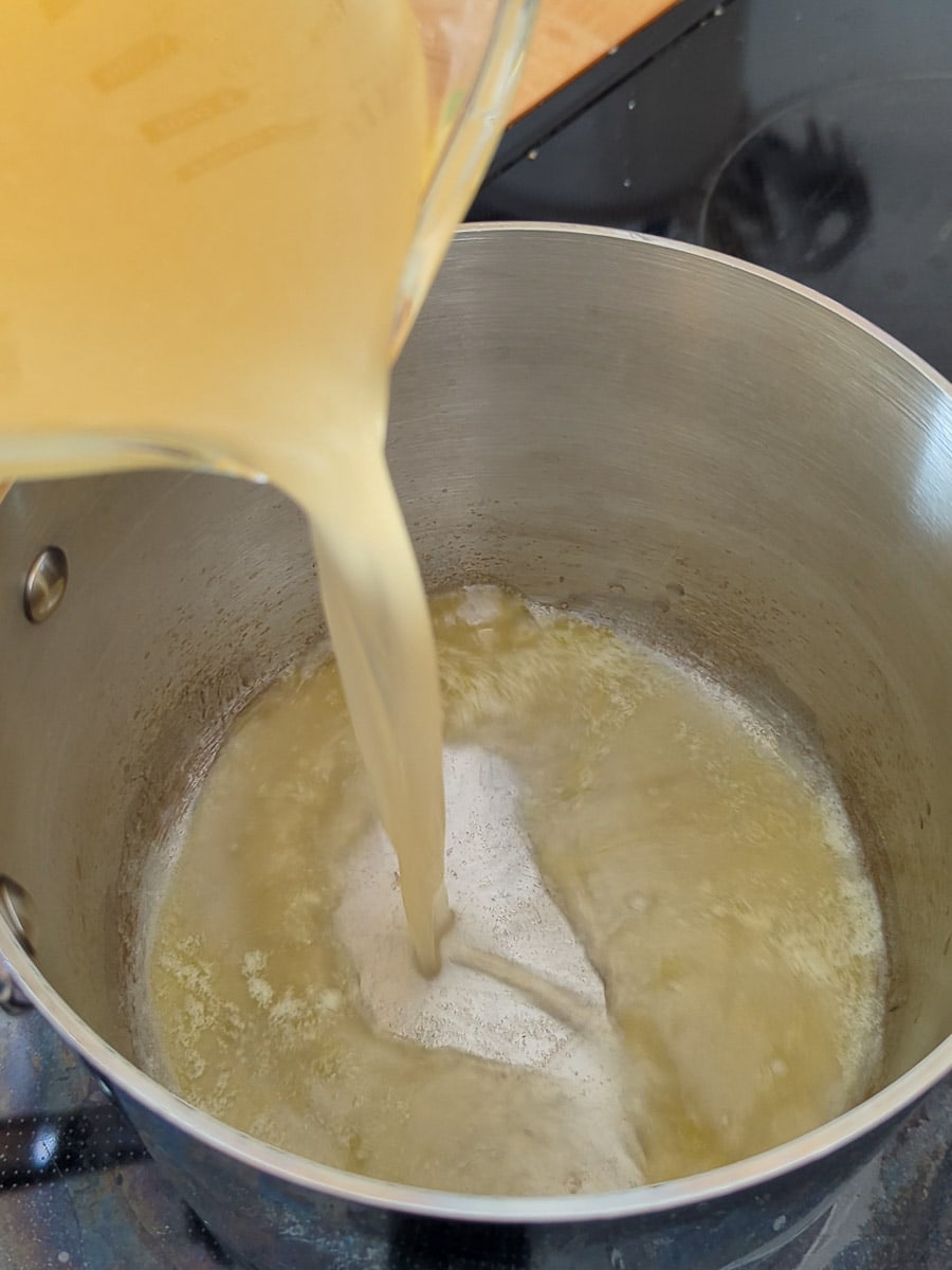Pouring liquid batter into a pot on the stove.