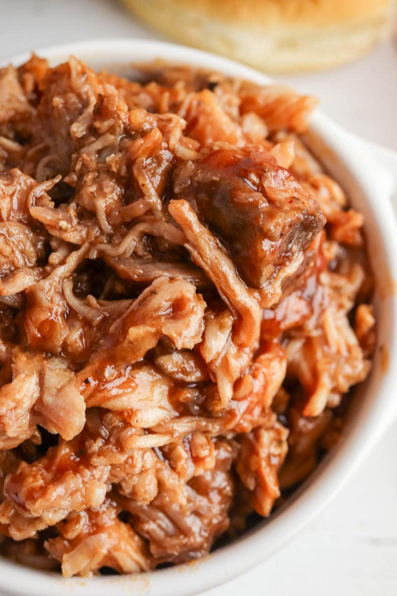 A close-up image of a bowl filled with juicy, shredded barbecue pork.