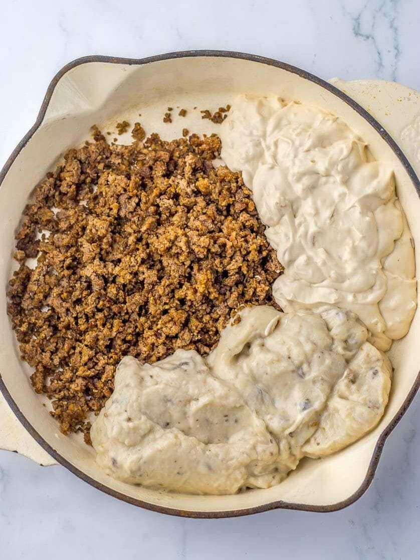 A casserole dish with separate portions of ground beef and creamy sauce, before mixing.