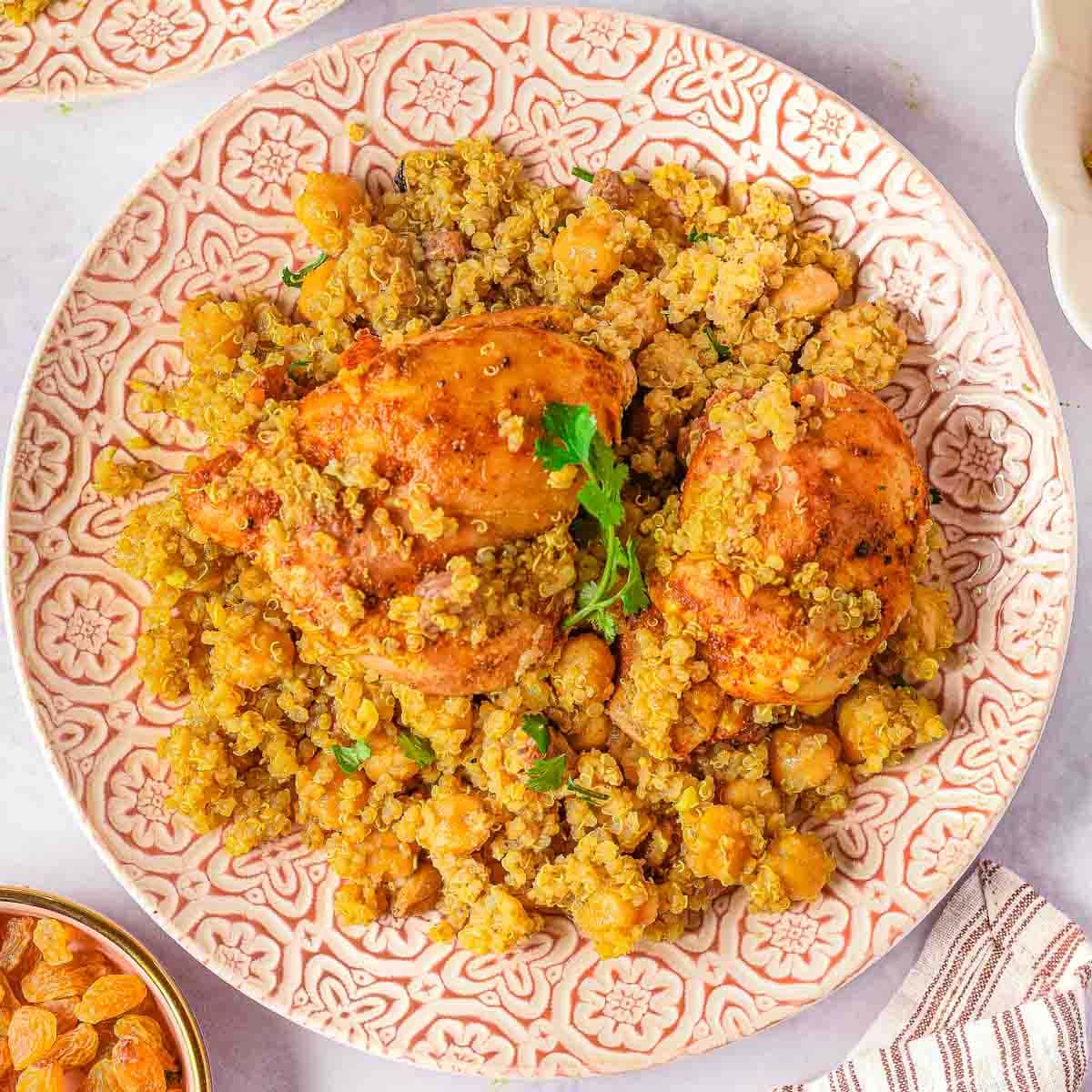 A plate of Moroccan chicken thighs tagine with quinoa and chickpeas, garnished with fresh parsley.