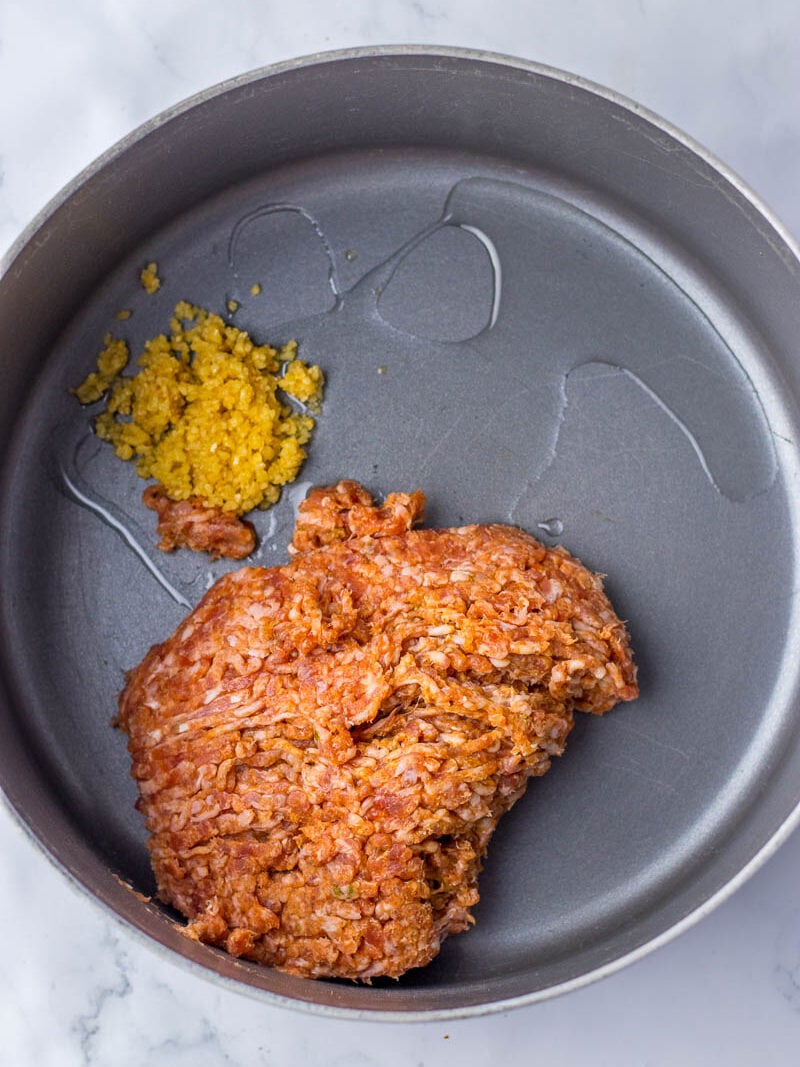 A gray frying pan containing a large piece of cooked ground meat and a small portion of mustard on the side.