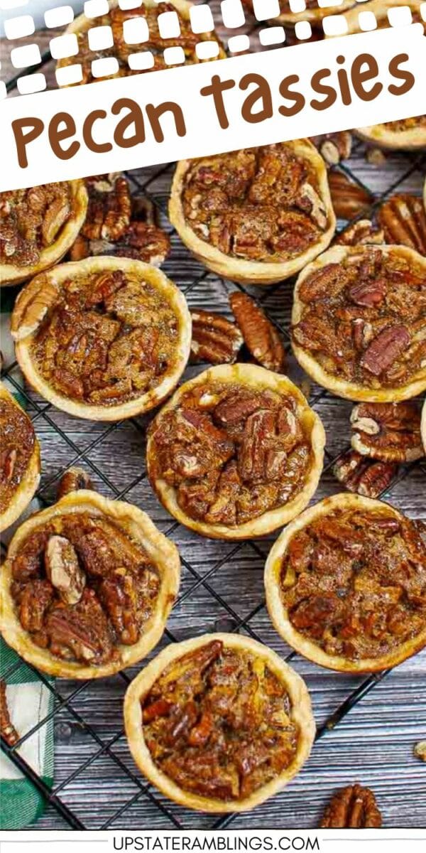 An assortment of small pecan tassies, or mini pecan pies, displayed on a cooling rack, with a few scattered pecans around them. Text at the top reads "Pecan Tassies.