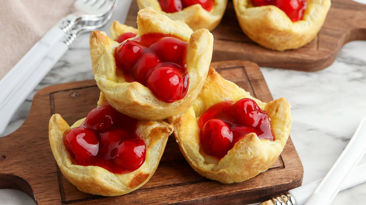 Cherry-filled pastries on a wooden serving board.