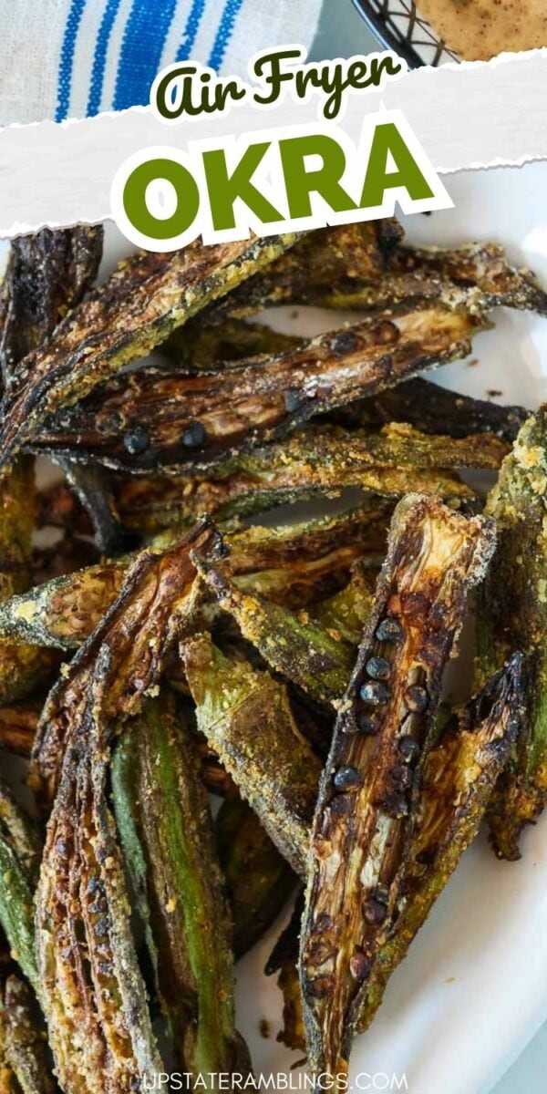 A plate of cooked okra slices with crispy edges, labeled "Air Fryer Okra." The okra is green with brownish char marks, and some pieces have seeds visible. Top of the image shows part of a blue-striped cloth.