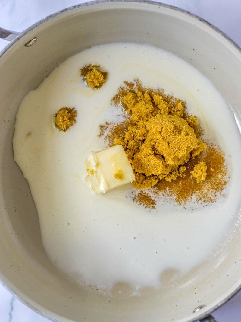 A saucepan containing milk, brown sugar, and a cube of butter.