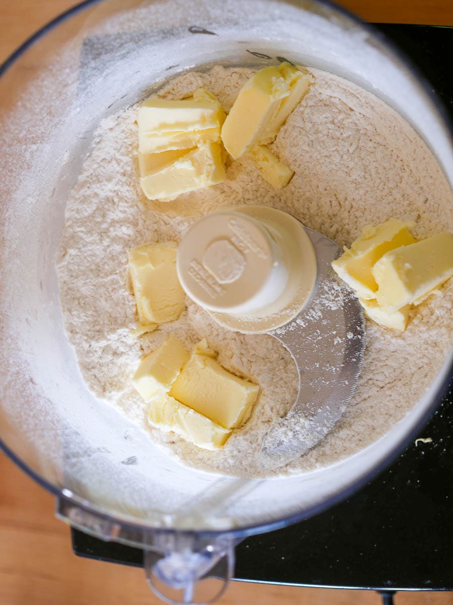 Butter chunks and flour in a food processor bowl.