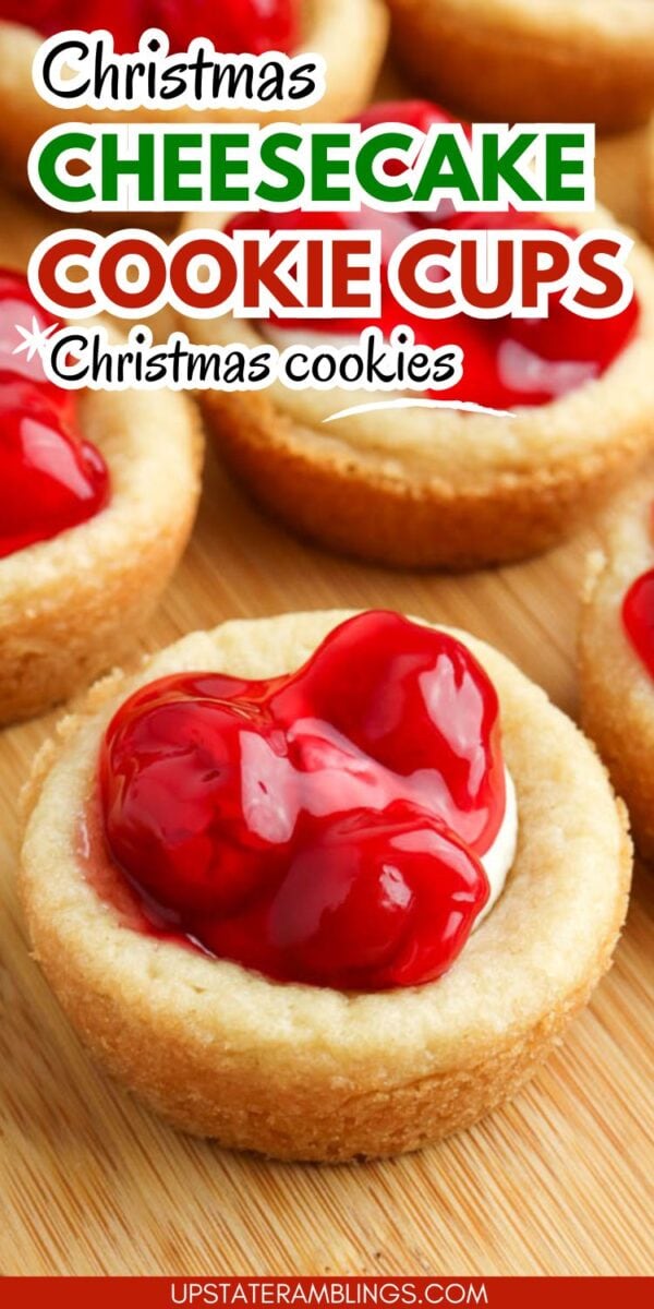Close-up of cherry cheesecake cookie cups topped with cherry filling, displayed on a wooden surface. Text on image reads "Christmas Cheesecake Cookie Cups Christmas cookies.