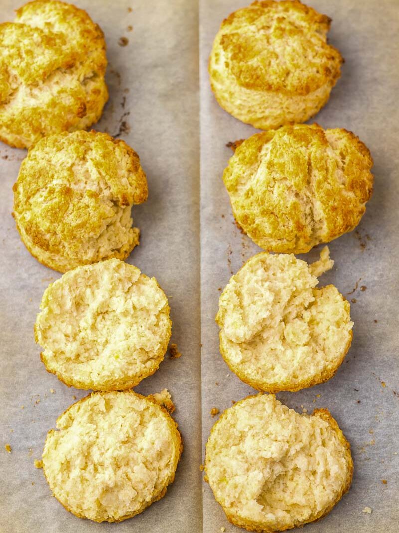 Golden brown biscuits are arranged on parchment paper, with some cut open to show the fluffy interior.