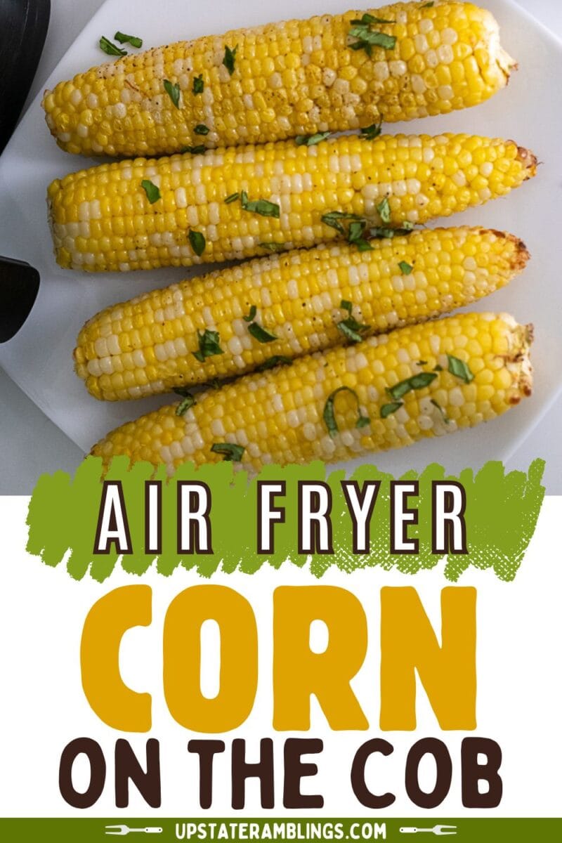 Four ears of cooked corn on the cob, garnished with chopped herbs, are arranged on a white plate with the text "Air Fryer Corn on the Cob" displayed below.