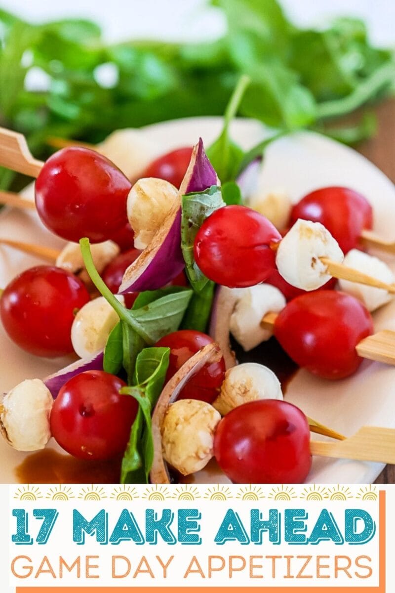 Skewers with cherry tomatoes, mozzarella balls, basil, and red onion on a plate. Text at bottom reads, “17 Make Ahead Game Day Appetizers.”.
