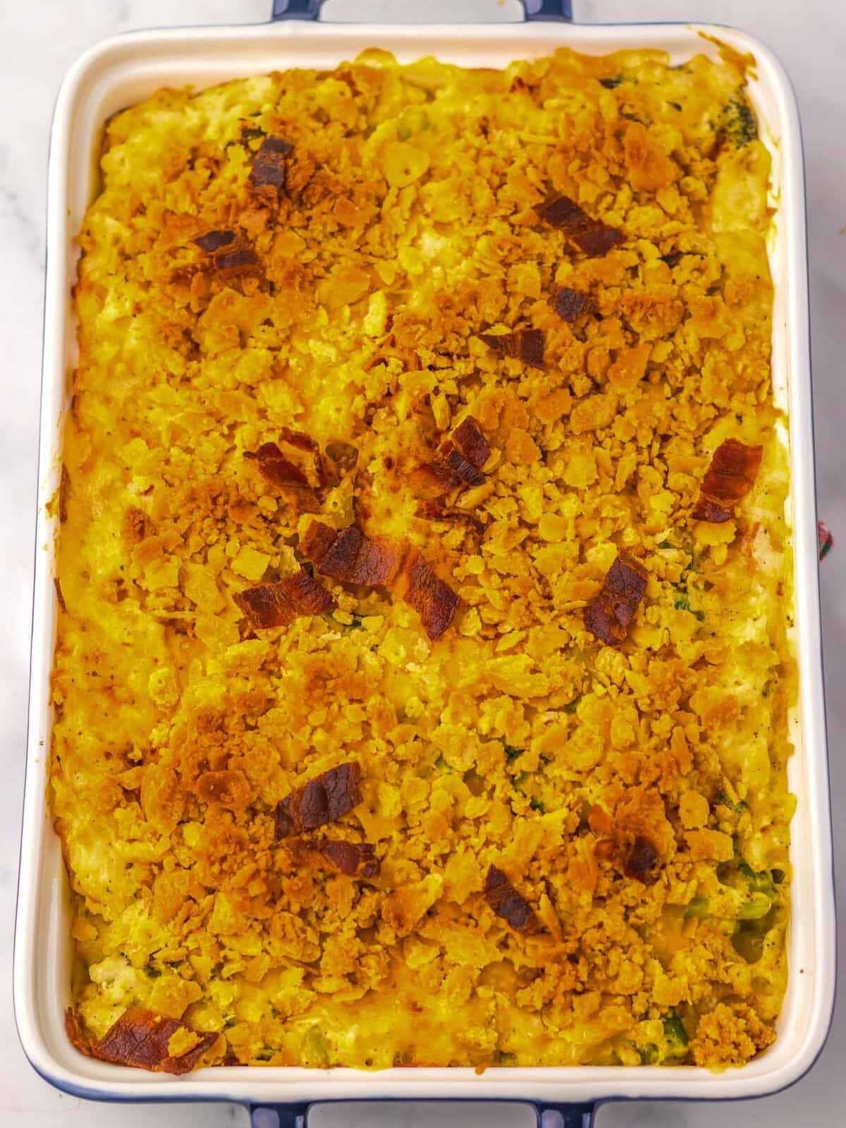 A baked casserole in a rectangular dish with a golden, crumbly topping, viewed from above on a white surface.
